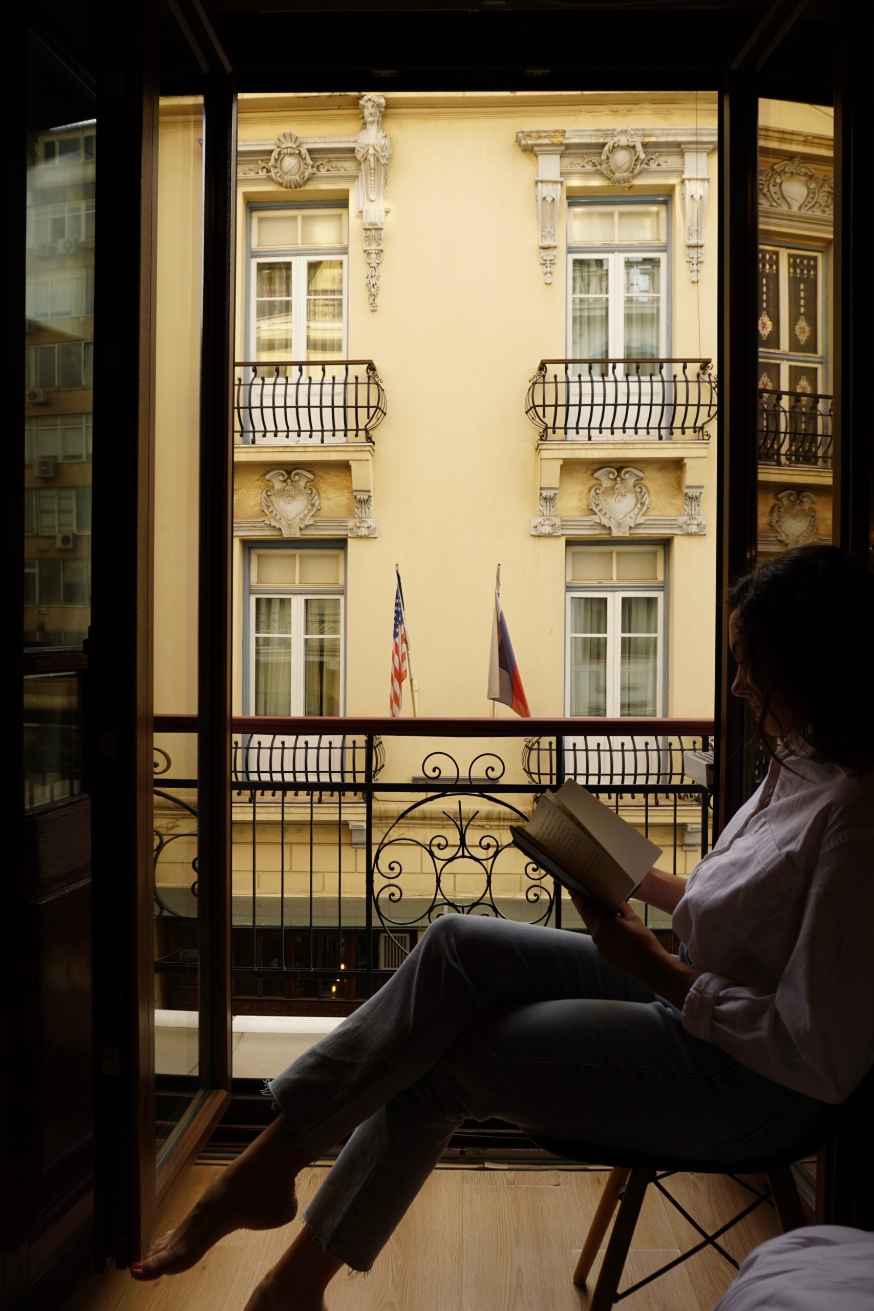 Alexa sits in front of a window reading a book in Thessaloniki, Greece