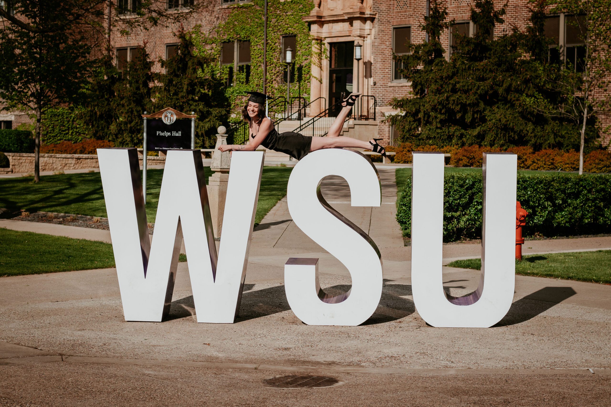 Alexa lays across 8 ft letters spelling out WSU in her graduation cap