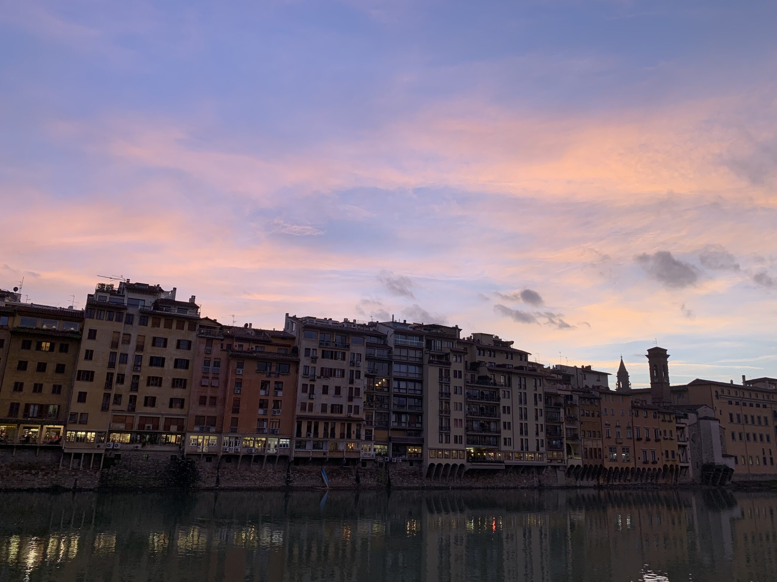 A blue and peach sunset stretches over the canal skyline in Florence, Italy