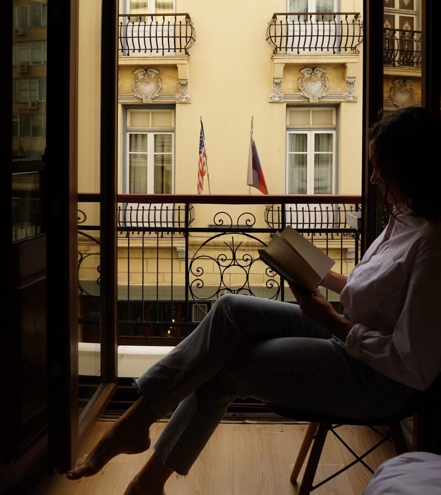 Alexa sits in the doorway reading a book. She is a silhouette against European architecture.