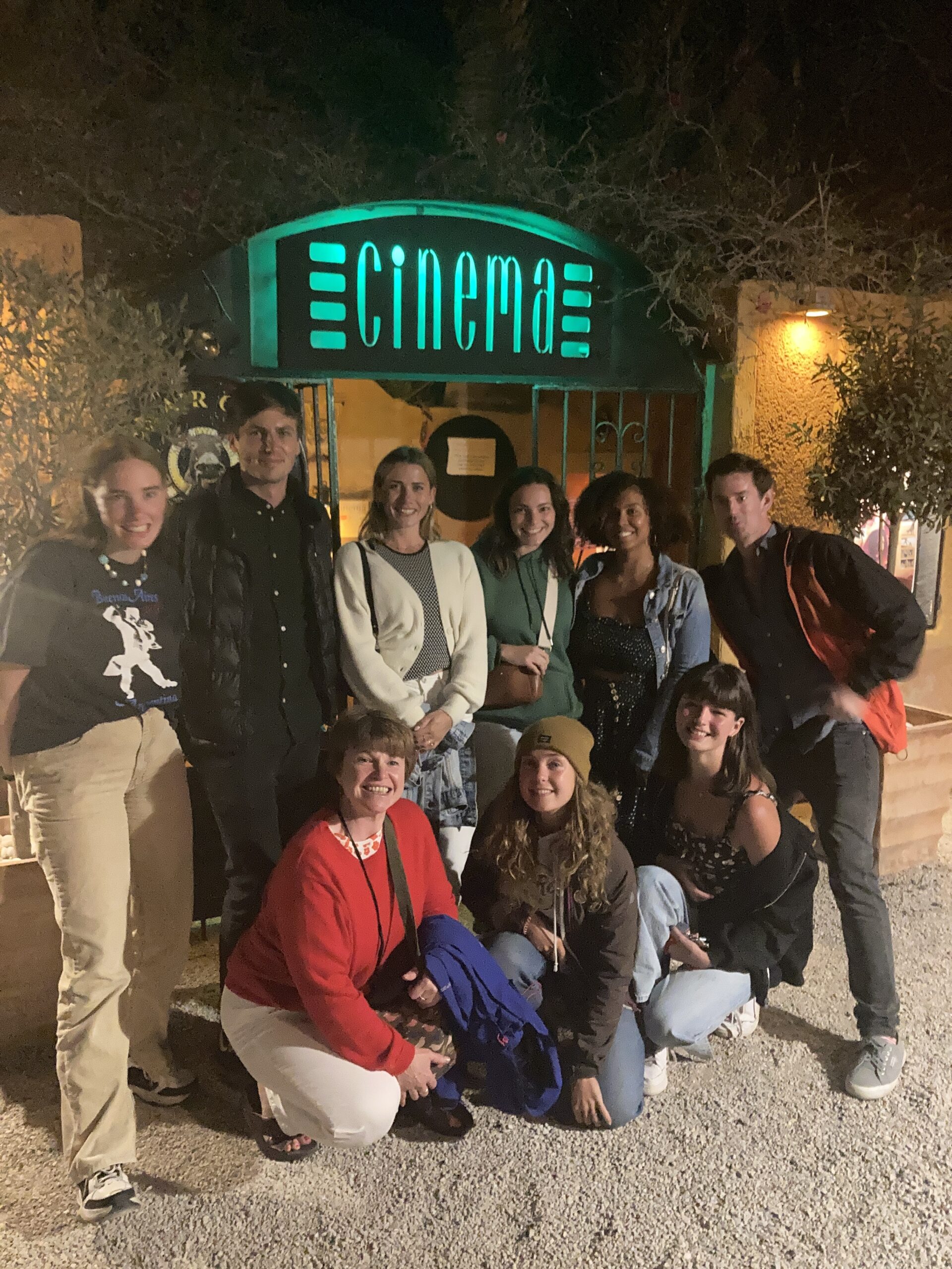 A group of people posing in front of a cinema marquee sign.