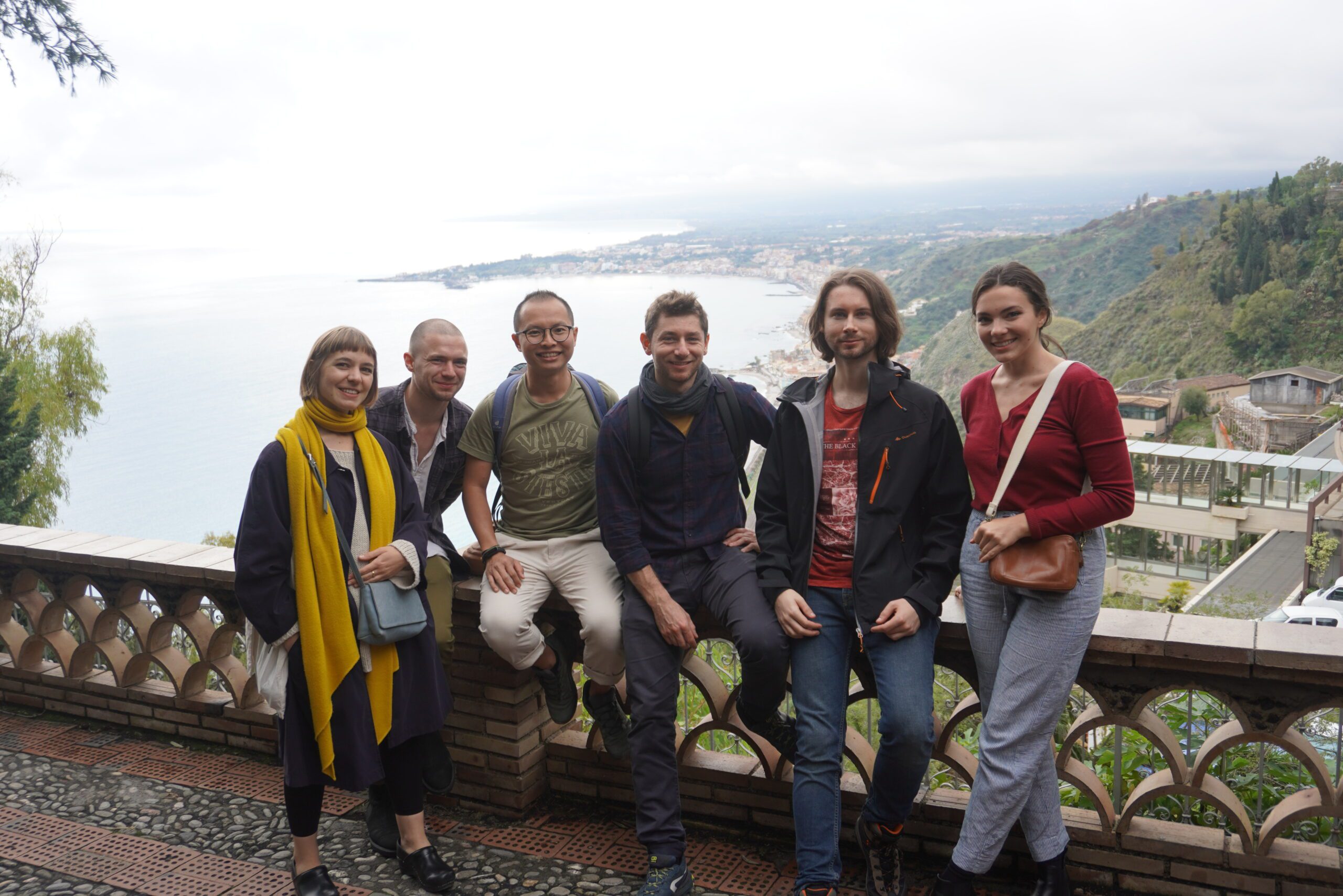 A group of people posing for a picture on a balcony in Catania.