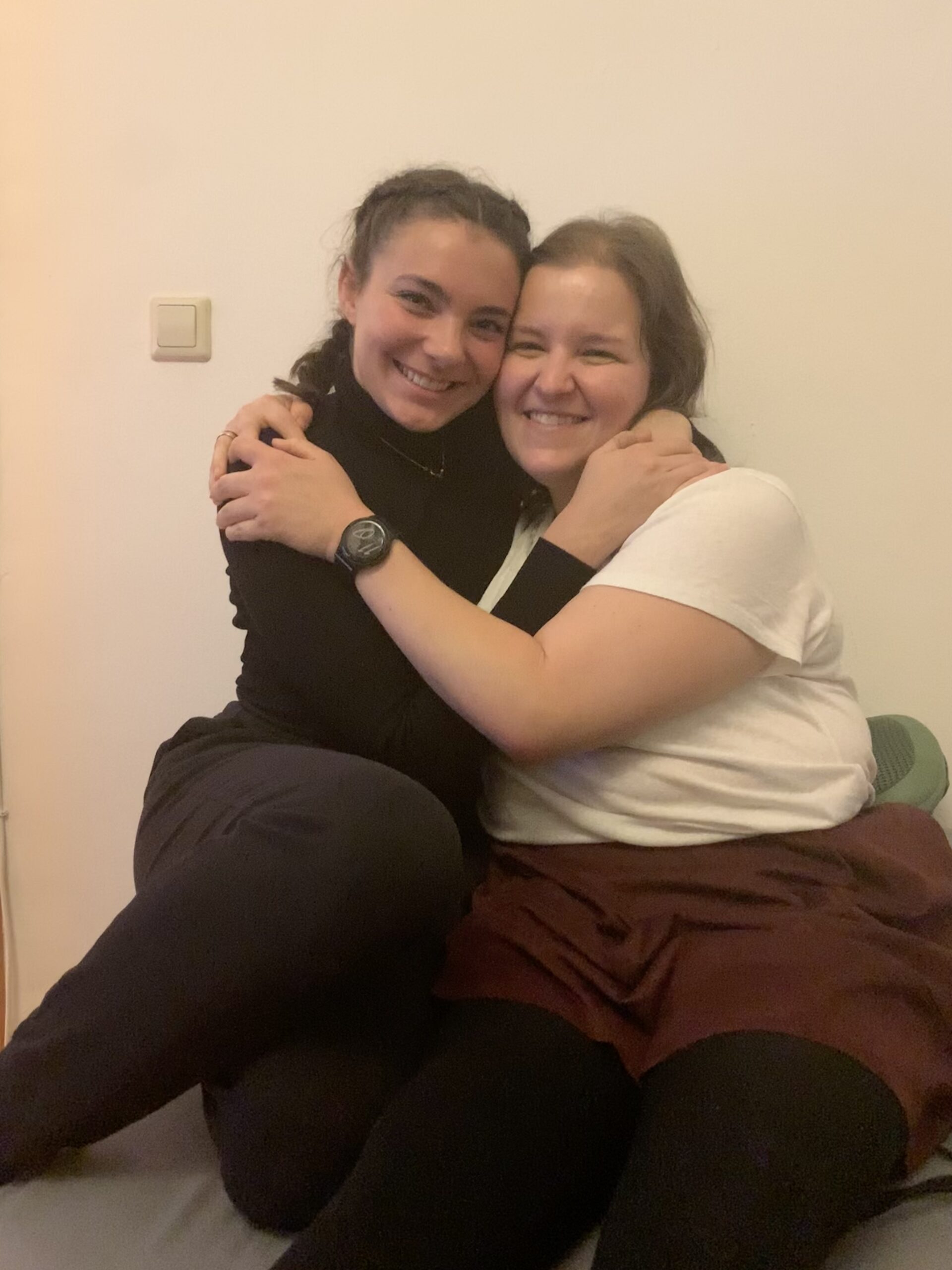 Two girls sharing affection on a couch in a cozy room.