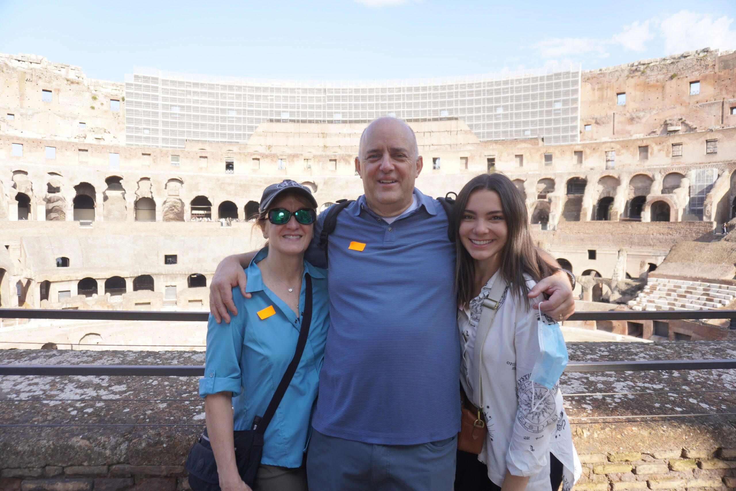 Three individuals striking a pose in front of an arena.