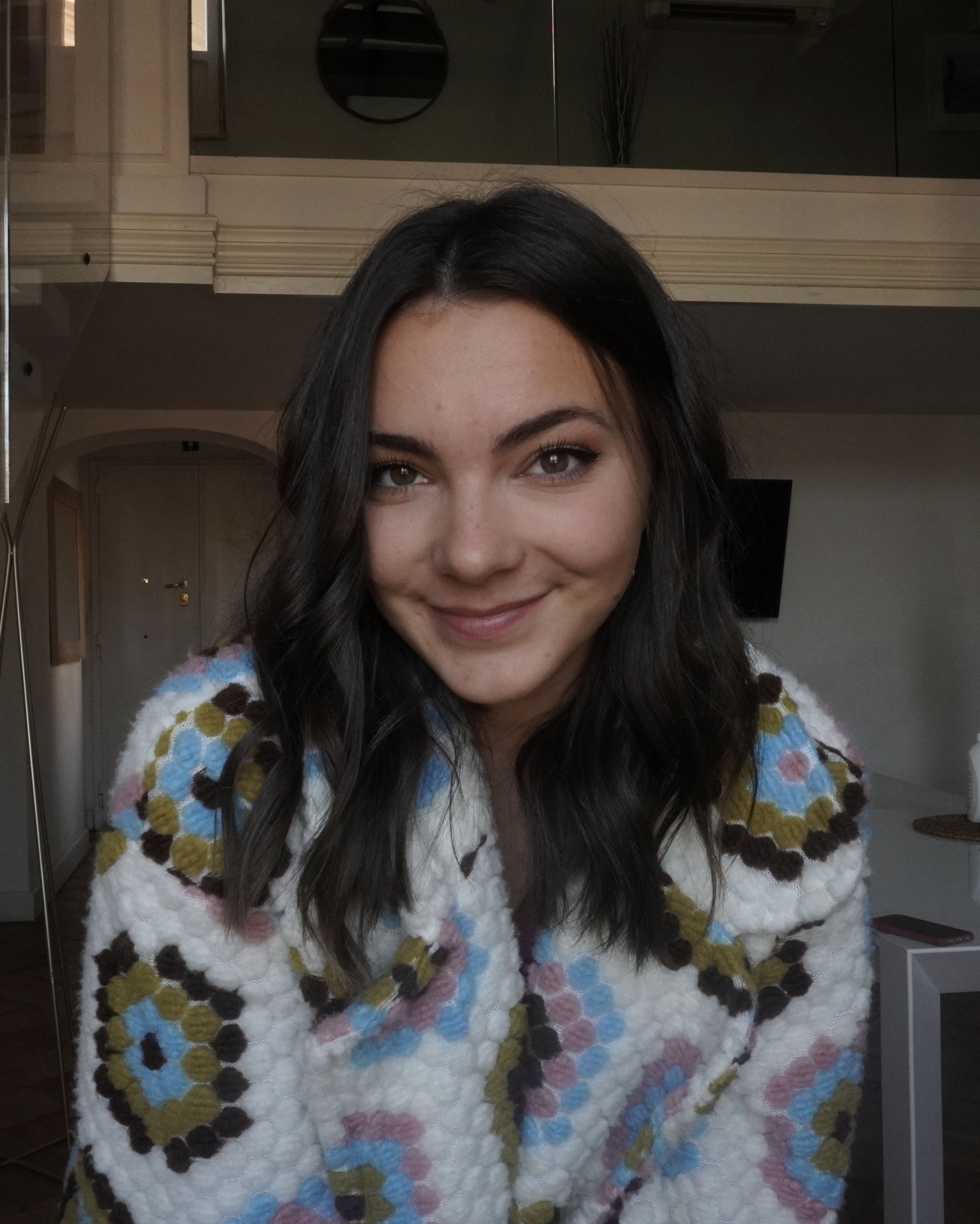 A woman in a colorful robe smiling for the camera.