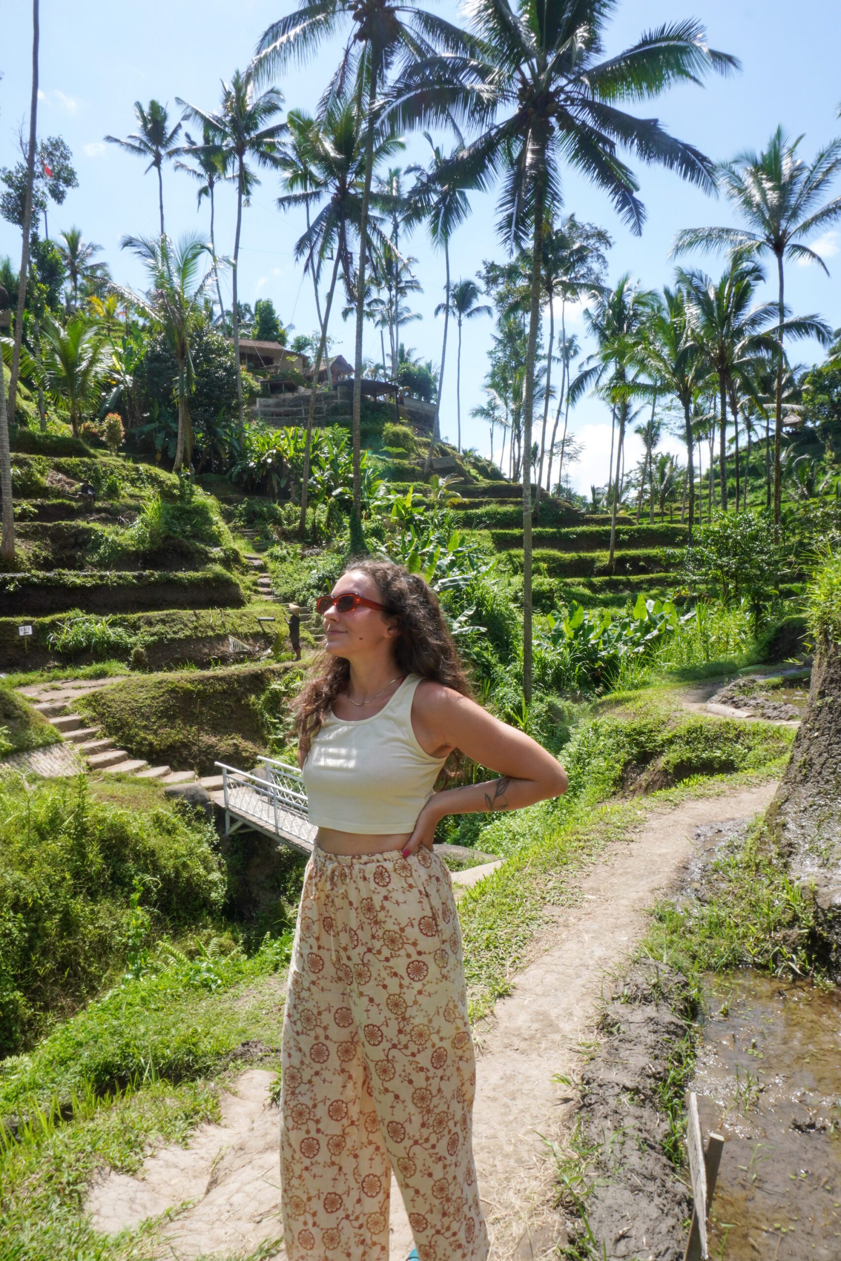 A woman standing on a path near rice terraces in Bali, marveling at the breathtaking landscape.