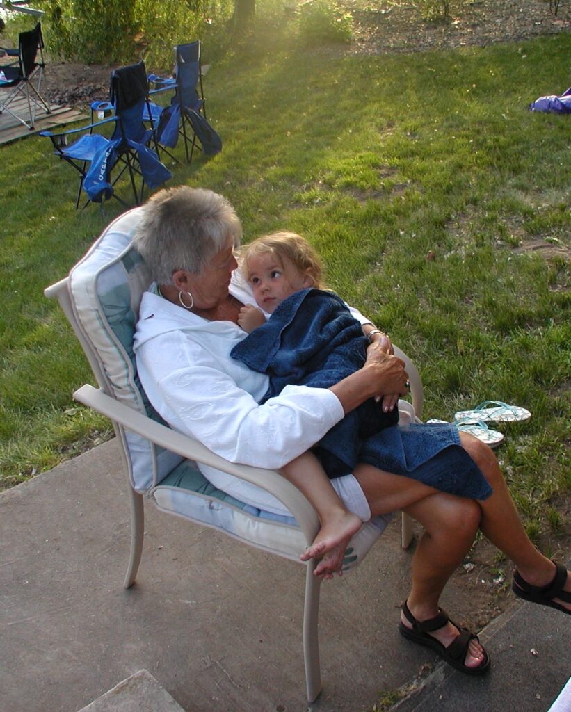 Grandma Barbie holding young Alexa in a lawn chair.