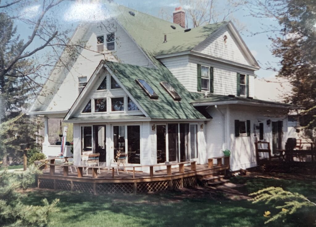 An old photo of a white house with a green roof.