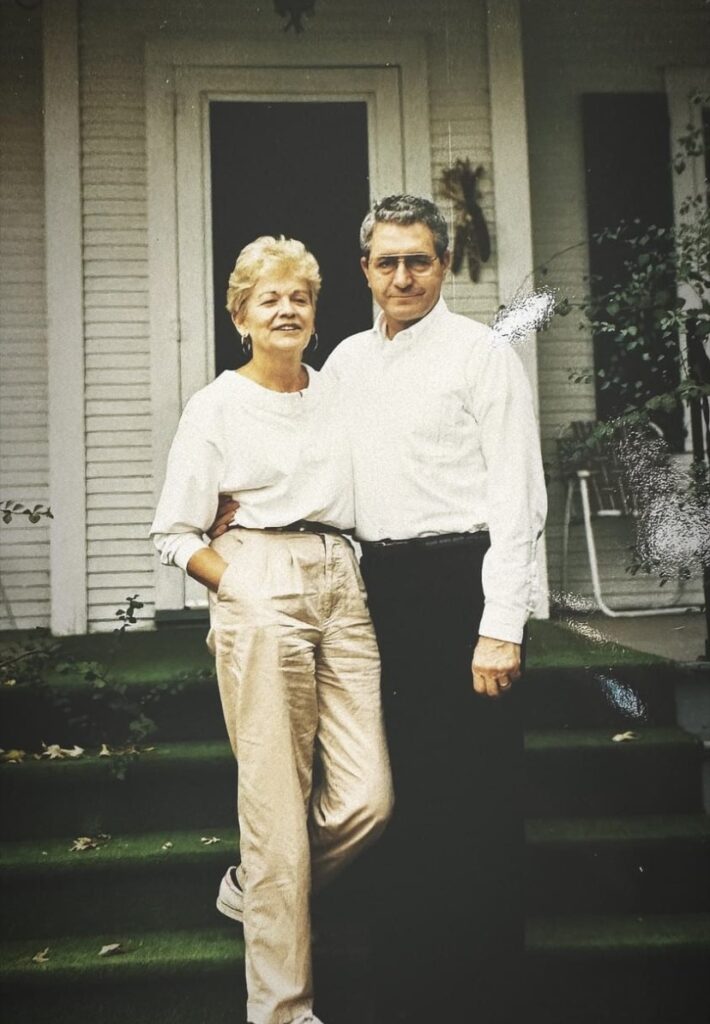 A man and woman standing on the steps of a house.