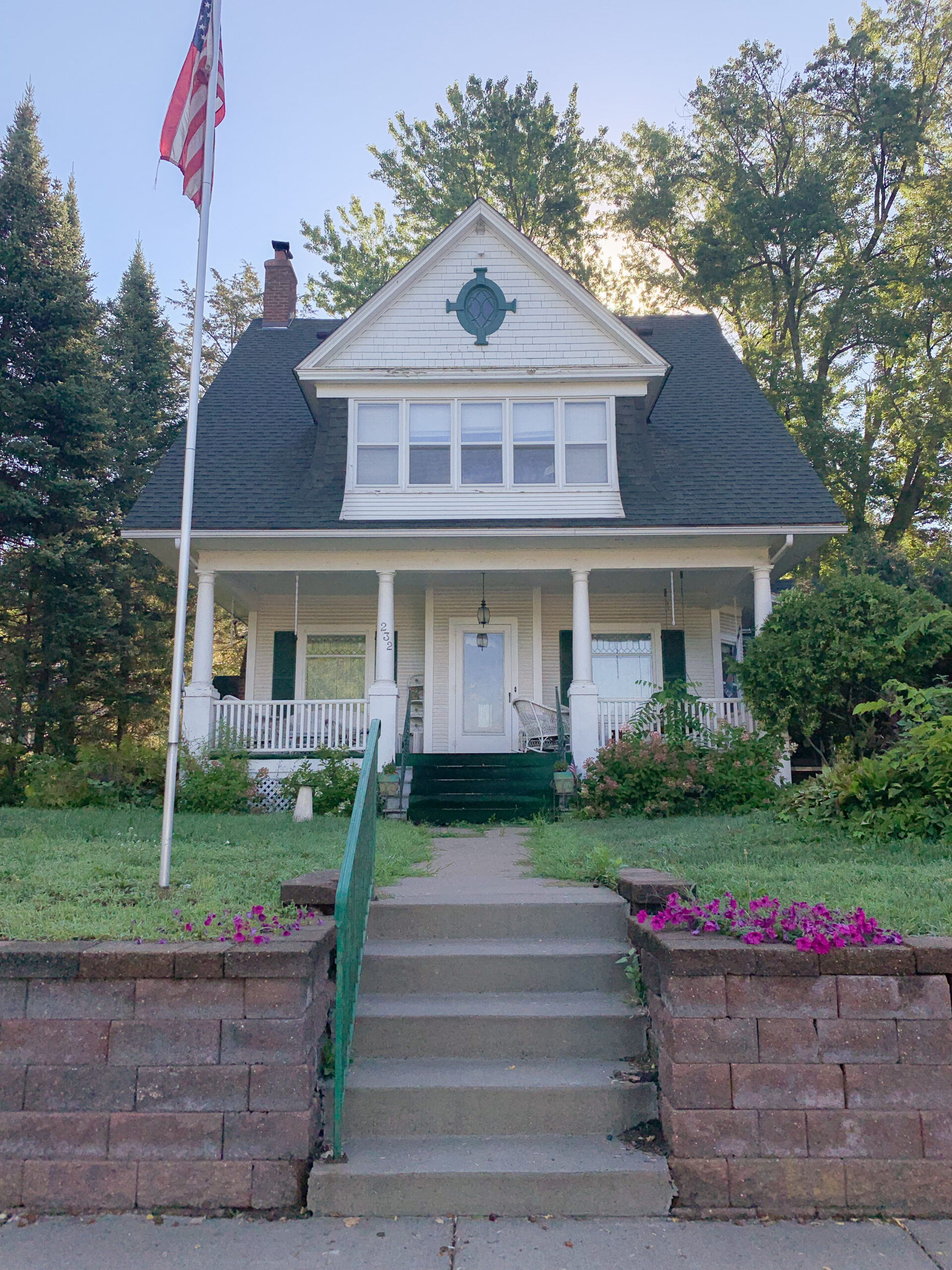 A white house with an american flag on the front porch.