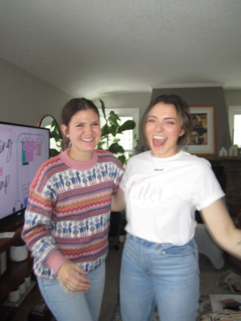 Two women standing in front of a tv in a living room.