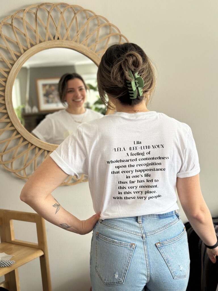 A woman is standing in front of a mirror wearing a t - shirt.