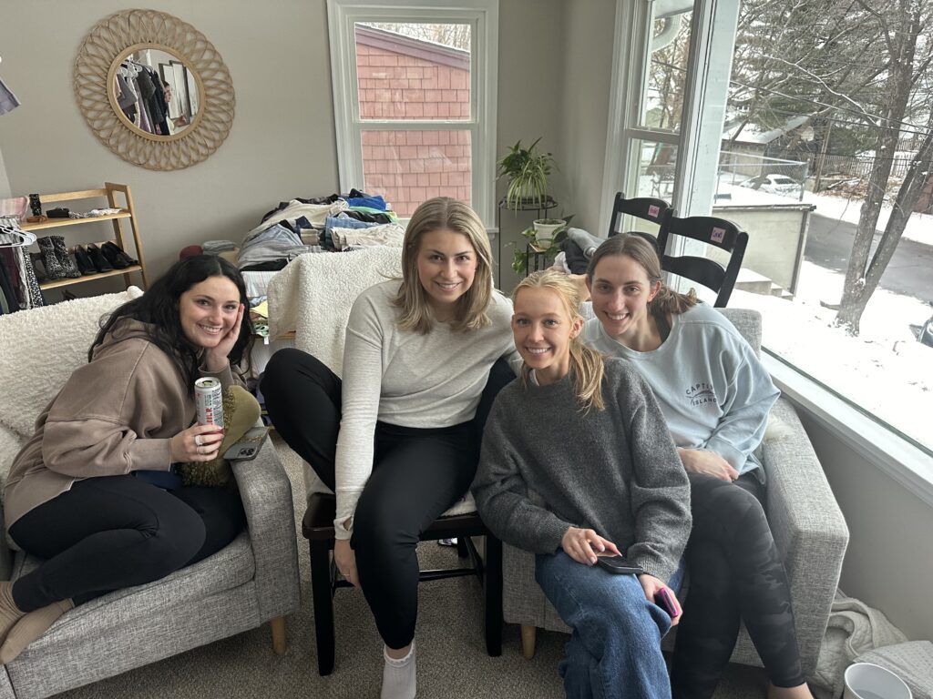 Four women sitting on a couch in a living room.