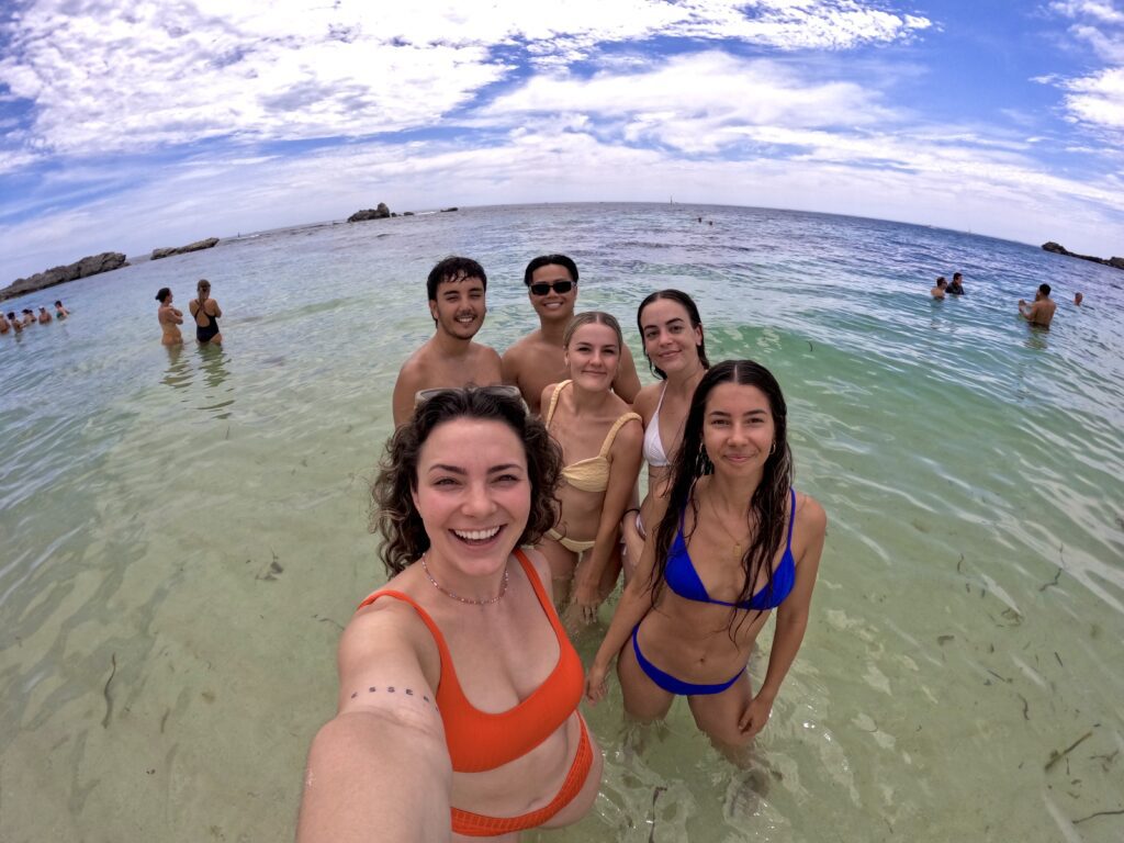 Group of friends taking a selfie in shallow beach waters.